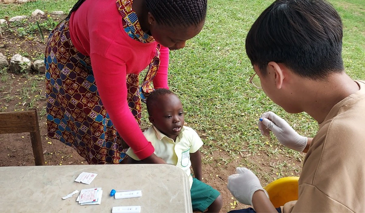 A volunteer giving a health check to a young child held by her mother